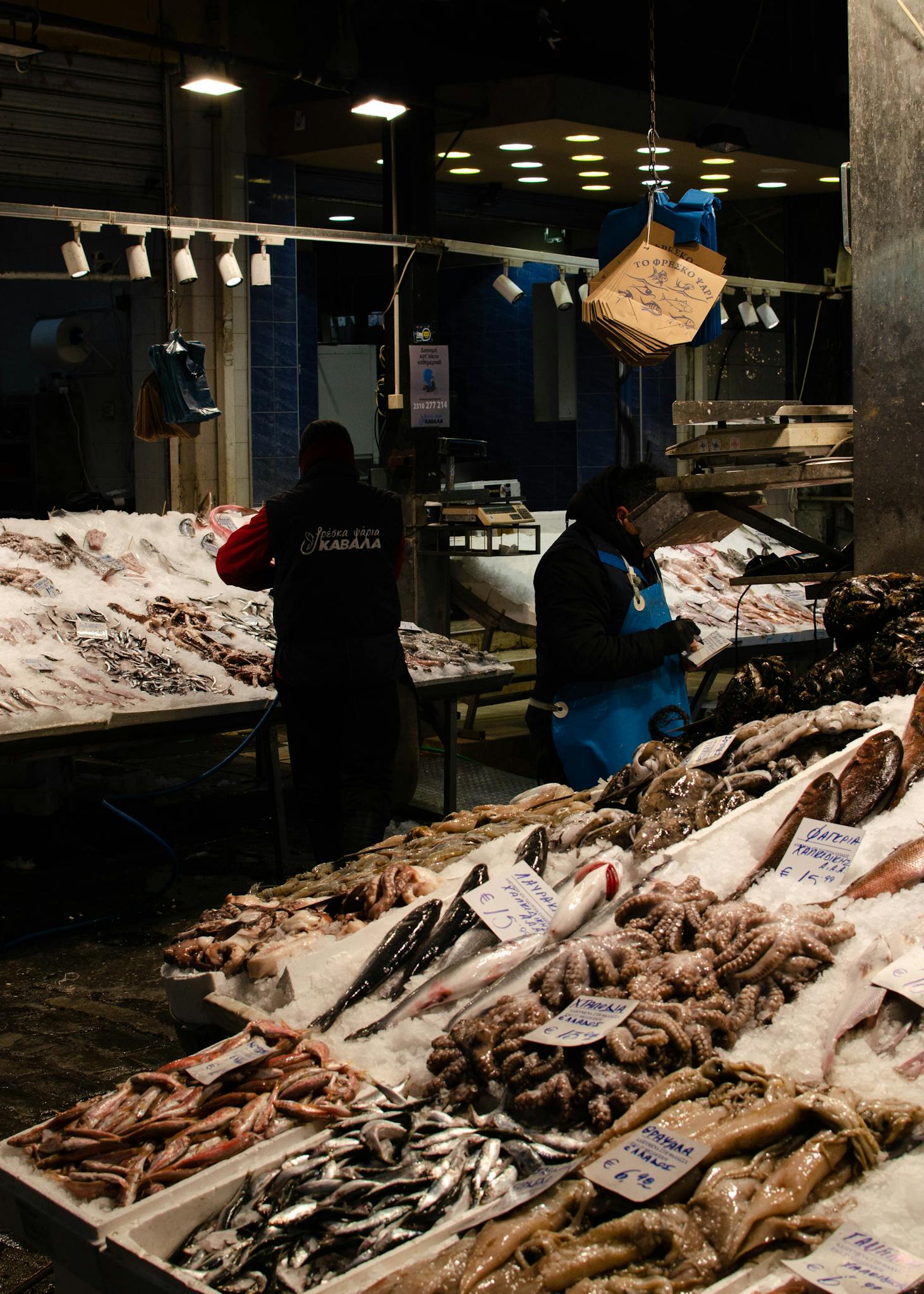 Bustling indoor fish market with fresh seafood and vendors under warm lighting.